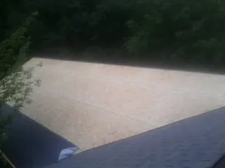 New OSB roof sheathing installed beside an existing shingle roof in Nowata
