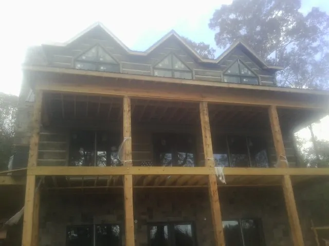 Dormers and porch framing on a large log home under construction — Roof Coating work by our crew in Nowata