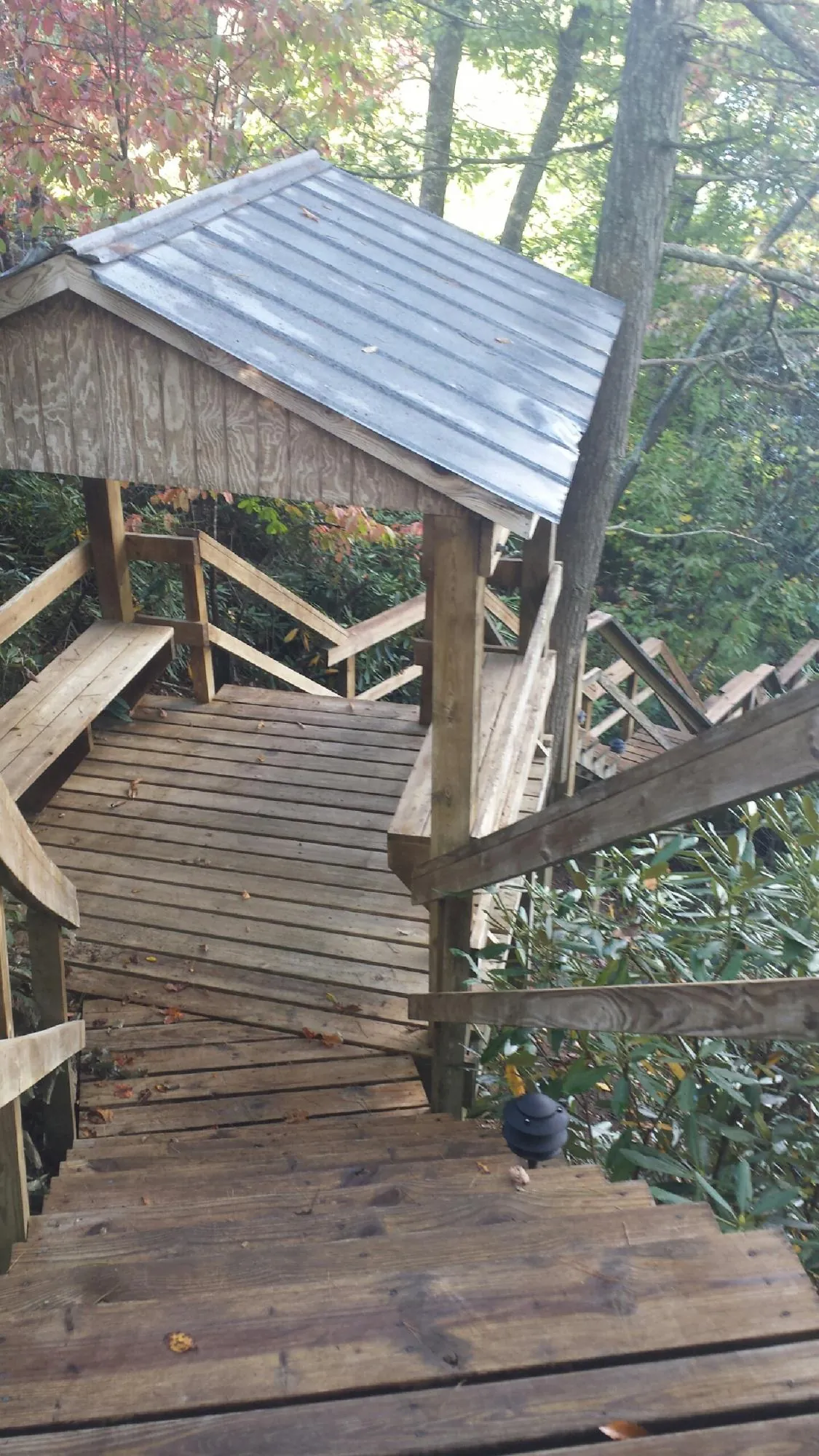 Metal roofed shelter over wooden steps on a wooded walkway — Skylight Repair & Installation work by our crew in Nowata