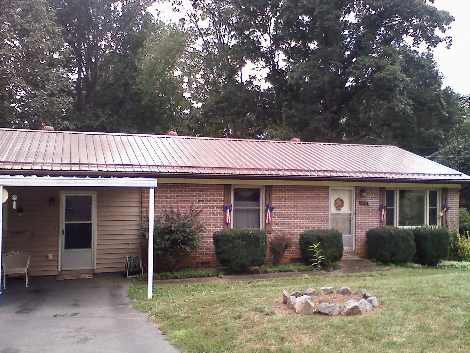 Bronze metal roof and carport on a brick ranch home — Roof Repair work by our crew in Nowata
